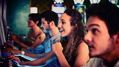 Girl celebrating a win at the slot machines with people surrounding her